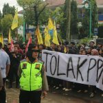 Demonstran melakukan aksi dengan membentangkan spanduk bertuliskan Tolak PPN 12%. (Aden/Fokuspers)