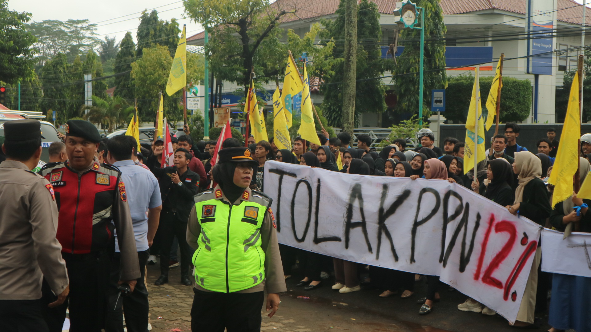 Demonstran melakukan aksi dengan membentangkan spanduk bertuliskan Tolak PPN 12%. (Aden/Fokuspers)